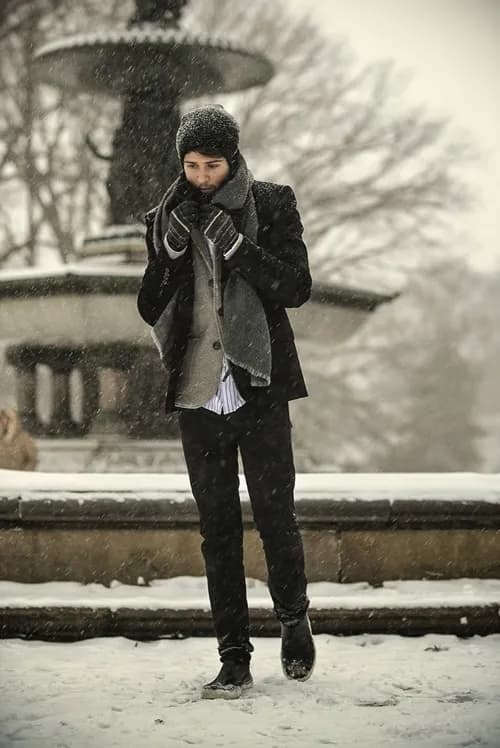 Homem agasalhado com luvas, cachecol, casaco e gorro para enfrentar o frio