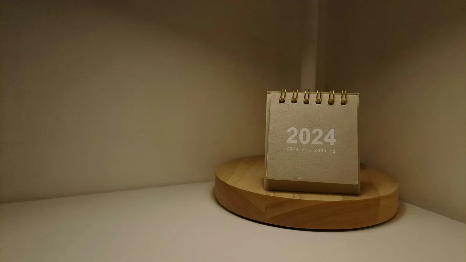Calendário de mesa minimalista sobre base de madeira, ilustrando os dias da semana em inglês