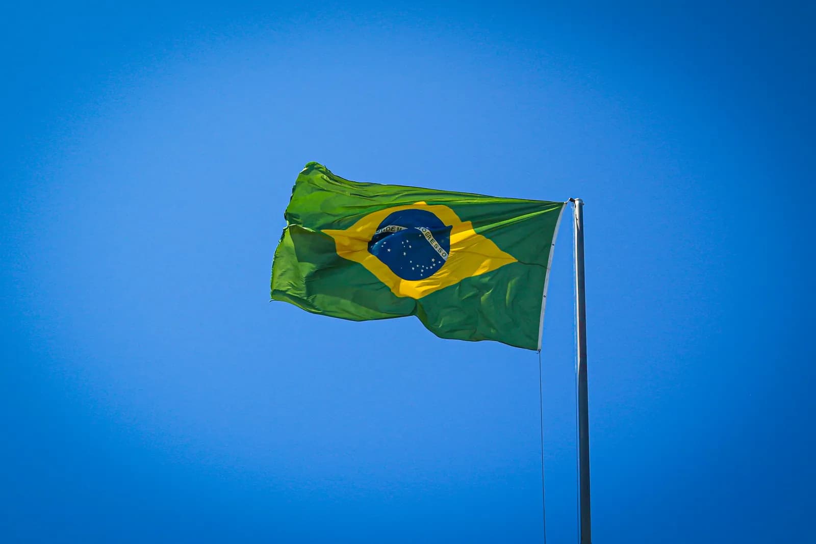Bandeira do Brasil tremulando ao vento sob céu azul — a língua oficial do Brasil