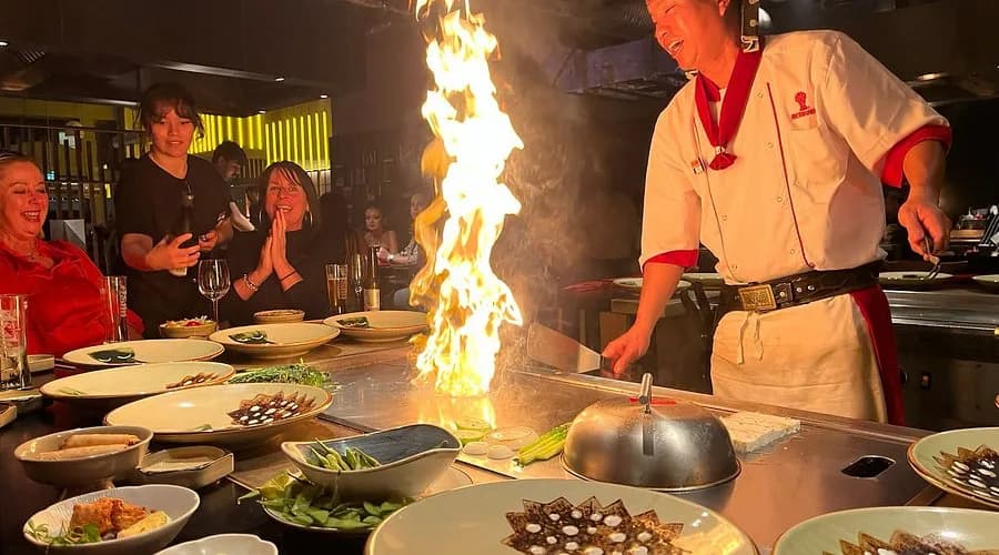 Chef do Benihana cozinhando na grelha em frente aos clientes