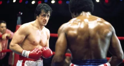 Sylvester Stallone caracterizado como Rocky Balboa na licao de ingles sobre o simple past