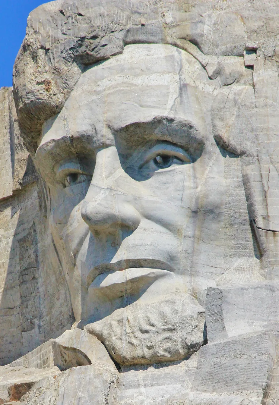 Imagem do rosto de Lincoln no Monte Rushmore: Close do rosto de Abraham Lincoln esculpido no Monte Rushmore, destacando seus traços imponentes.