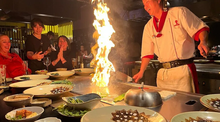 Chef do Benihana cozinhando na grelha em frente aos clientes