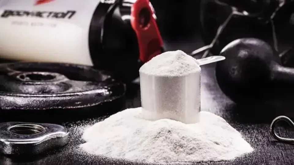 Pote de creatina em pó ao lado de uma dose medida sobre a mesa