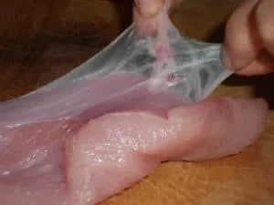 Peito de frango cru mostrando a fina membrana de fáscia sobre a carne