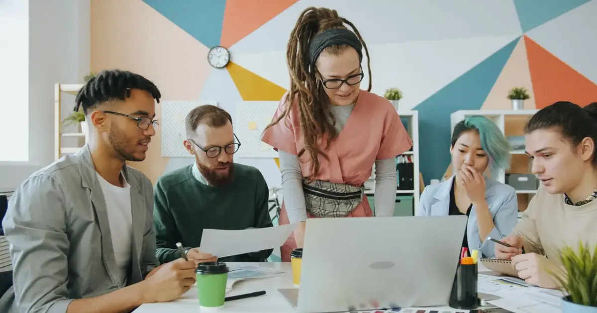 Equipe trabalhando junta em volta de um laptop: get the ball rolling, move the needle