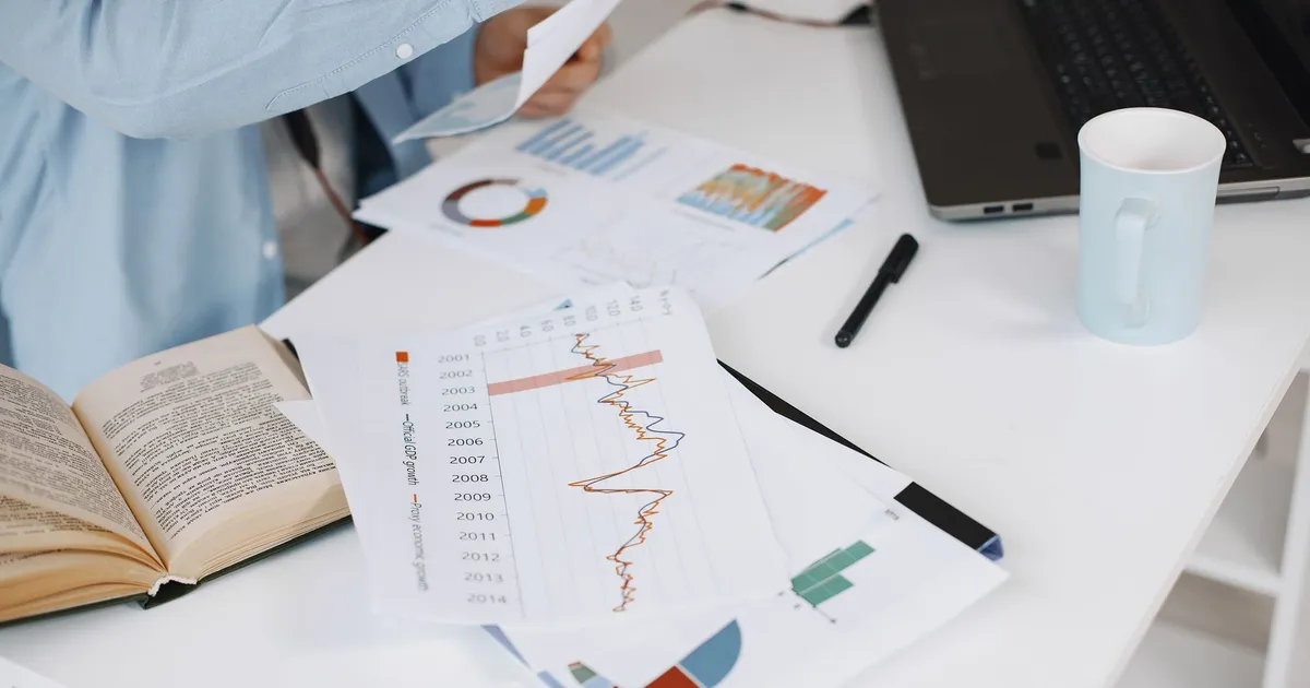 Gráficos financeiros sobre a mesa, ilustrando Inglês para Negócios: Investir na Argentina, Economia e Política
