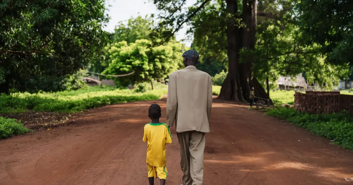 Pai e filho caminhando por uma estrada de terra na fazenda