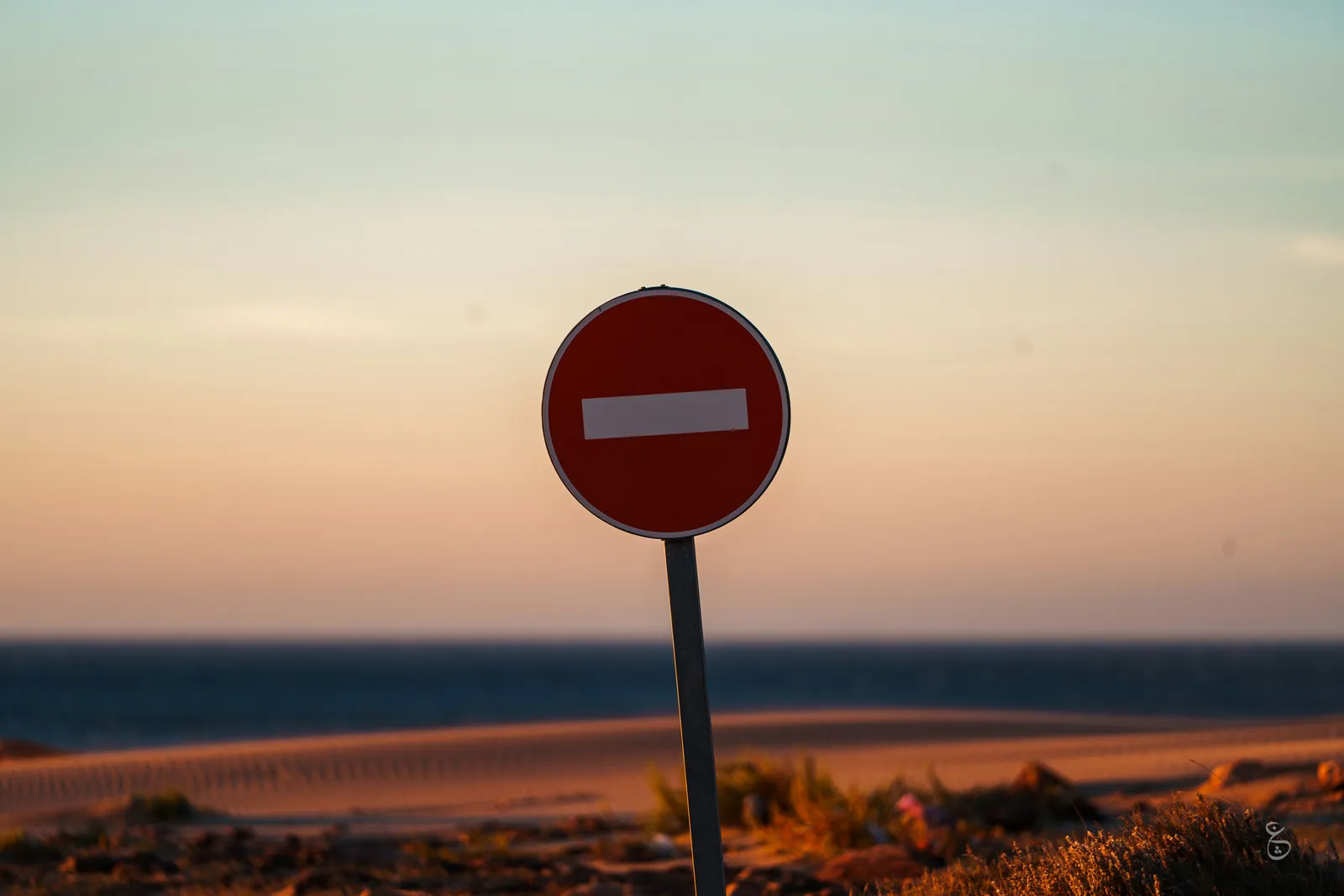 Placa vermelha de proibido ao entardecer, representando o imperativo negativo (don't) em inglês