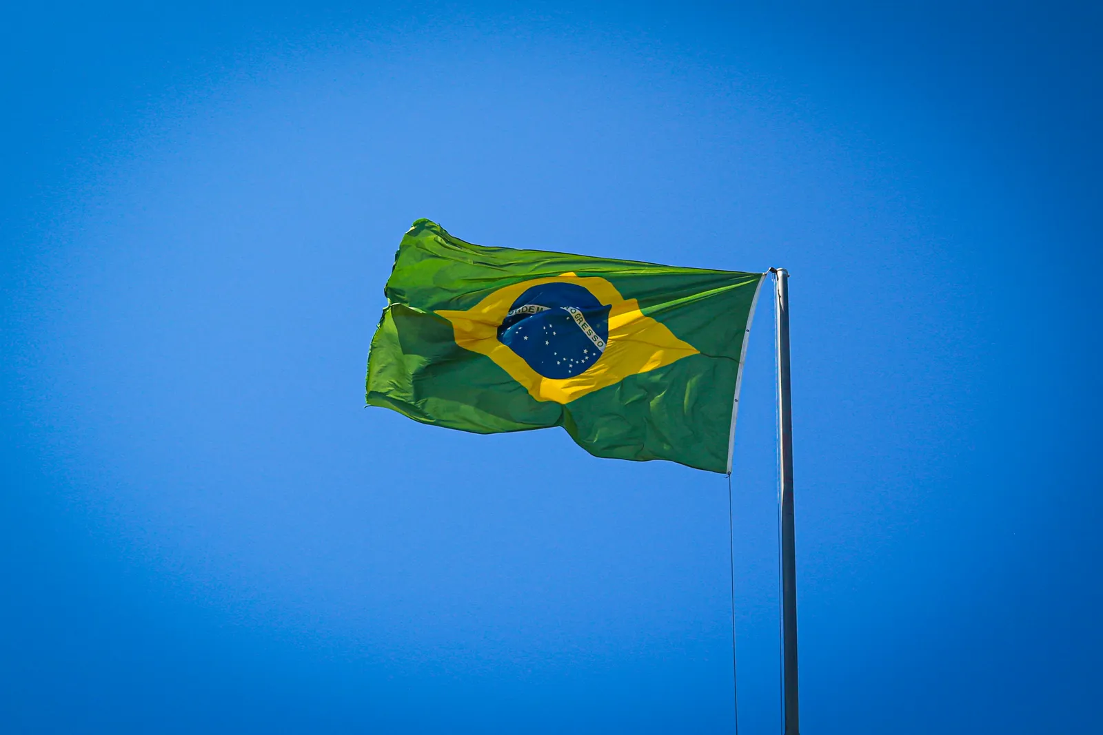 Bandeira do Brasil tremulando ao vento sob céu azul — a língua oficial do Brasil