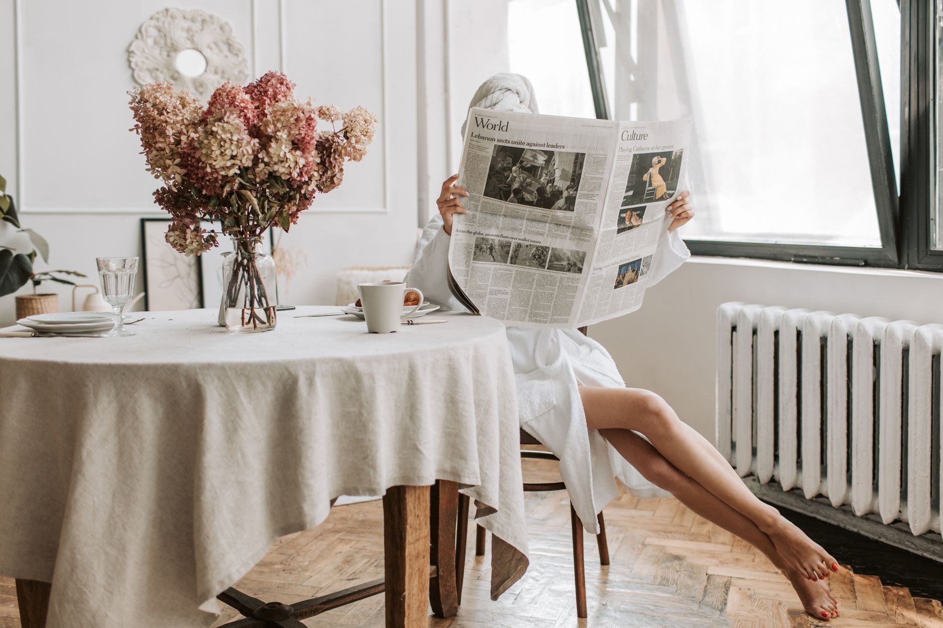 Mulher lendo o jornal em inglês com um café pela manhã, aprendendo inglês com notícias.