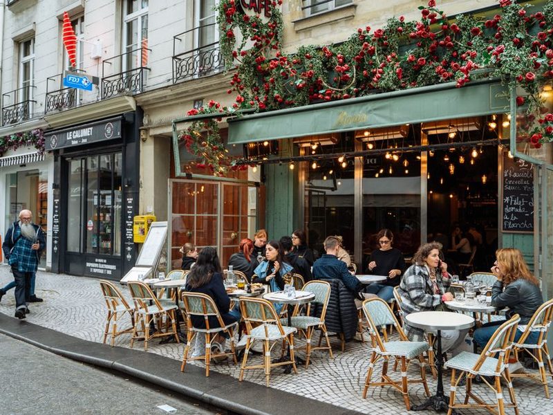 Café de calçada em Paris com mesas redondas e cadeiras de vime — cenário do texto em inglês there is there are