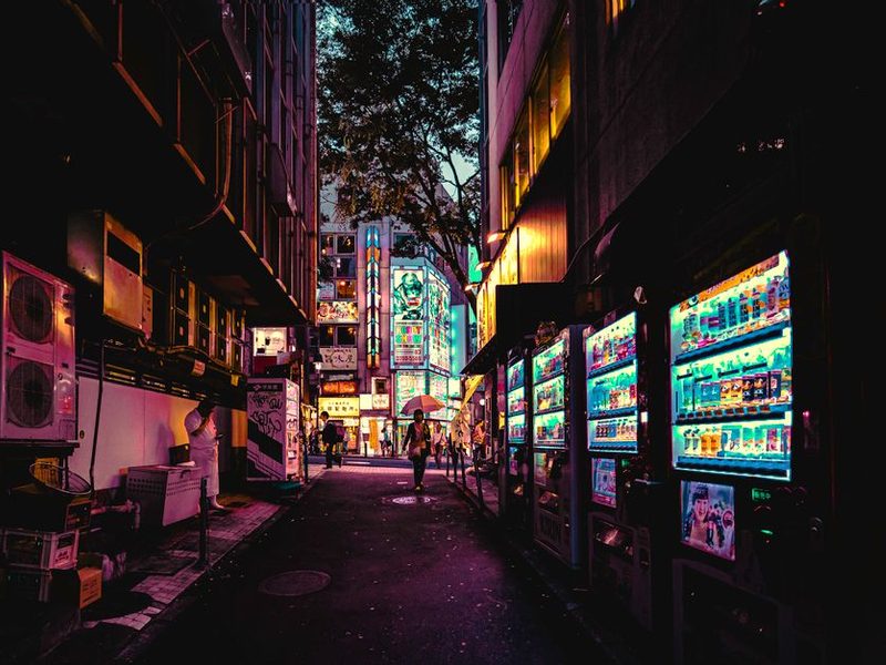 Rua de Tóquio à noite com máquinas de venda automática iluminadas
