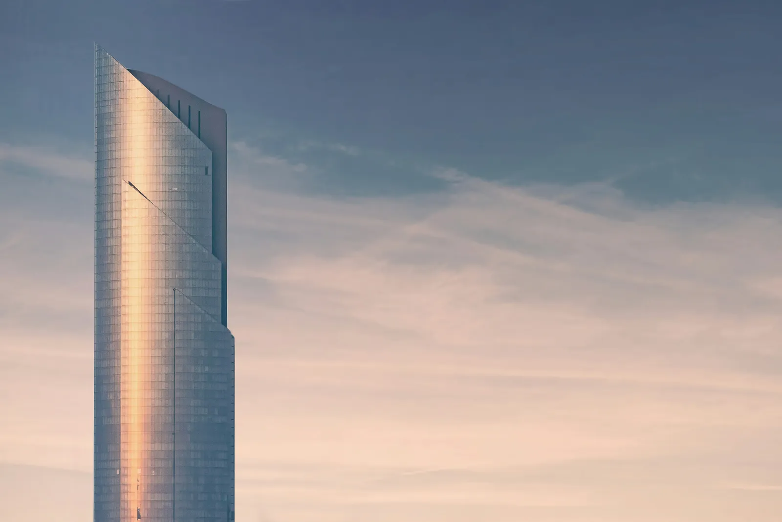 Arranha-céu altíssimo ao pôr do sol, ilustrando o superlativo em inglês (the tallest)