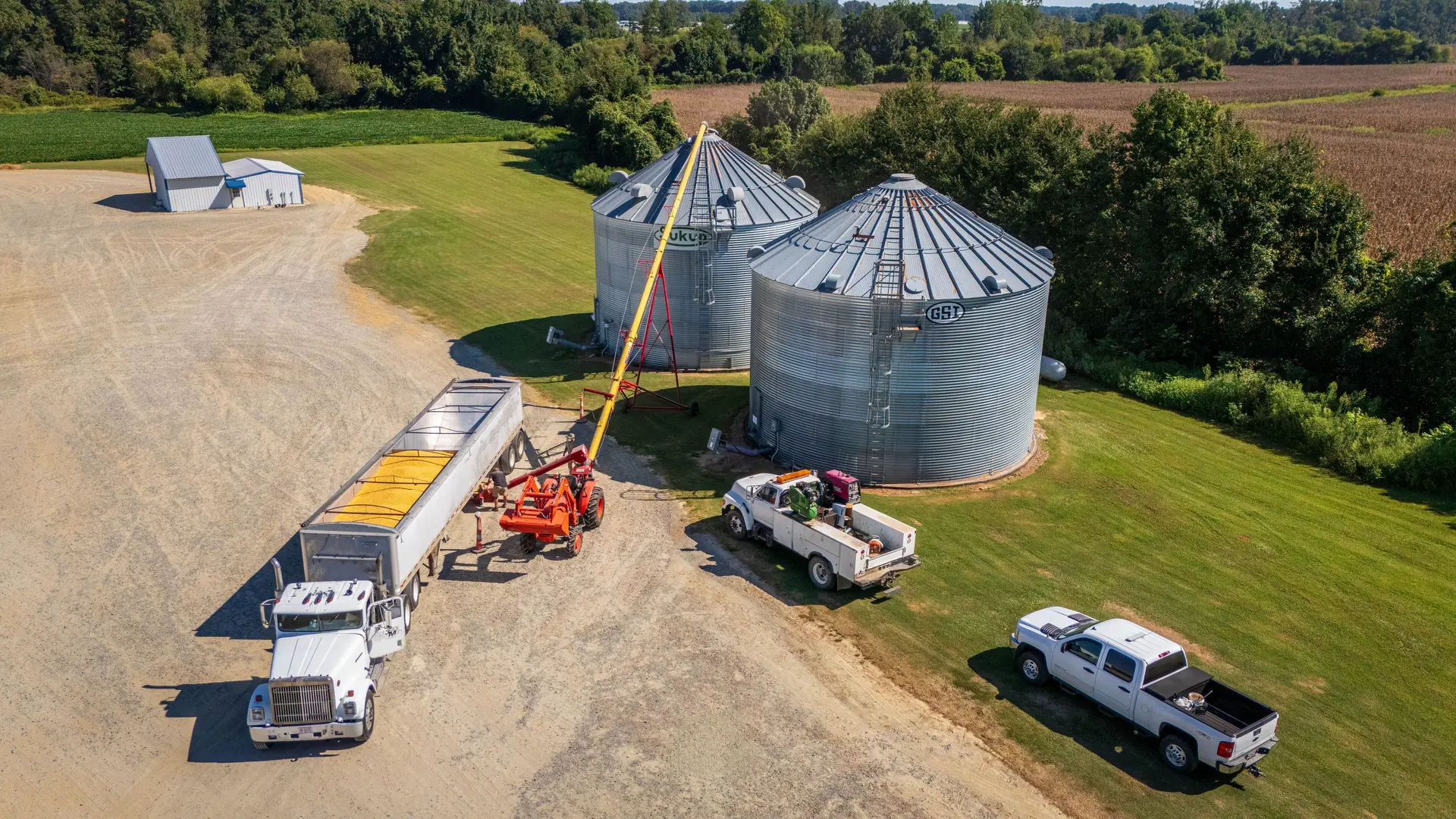 Silos, caminhões e caminhonetes na sede de uma fazenda, vistos do alto