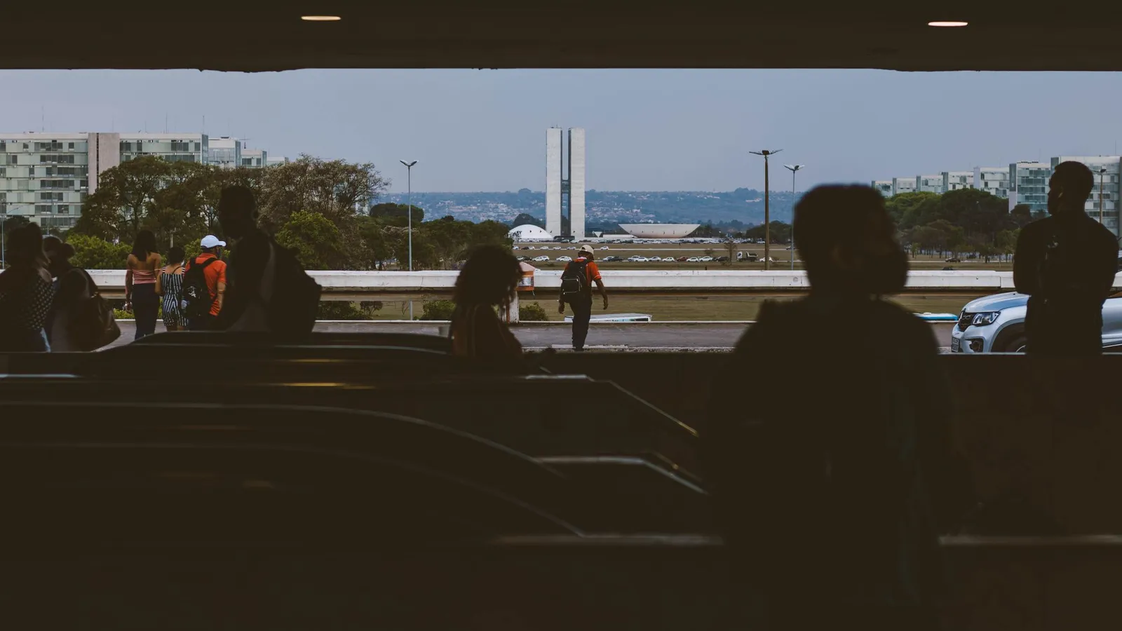 Silhuetas de pessoas numa passagem subterrânea de Brasília, com o Congresso Nacional ao fundo