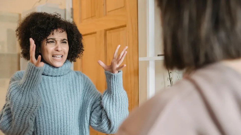 Mulher discutindo, com as mãos abertas e cara de indignação