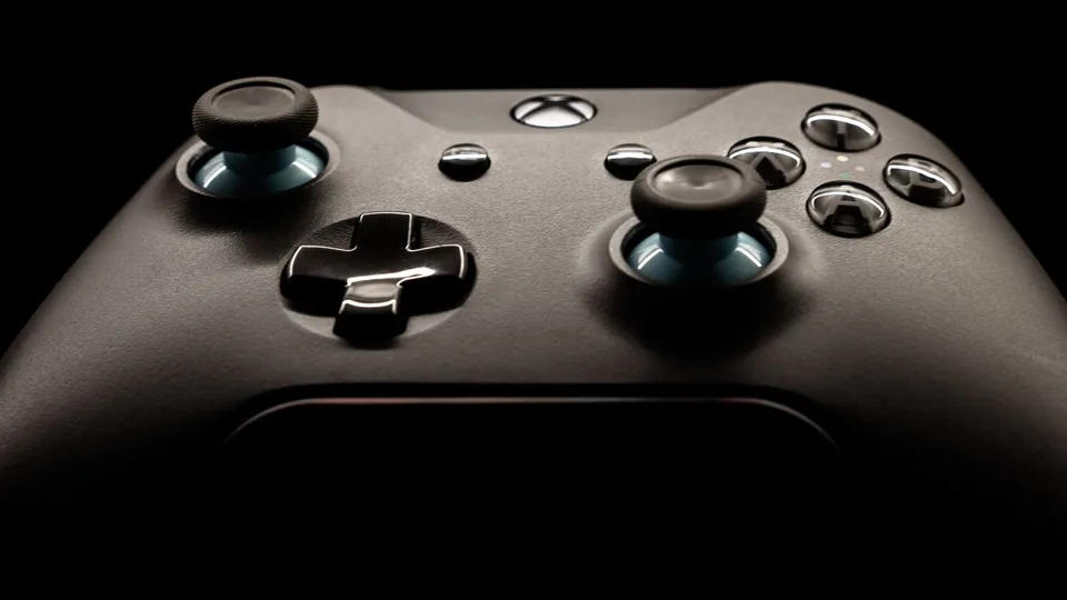 Controle de videogame preto em close, no escuro