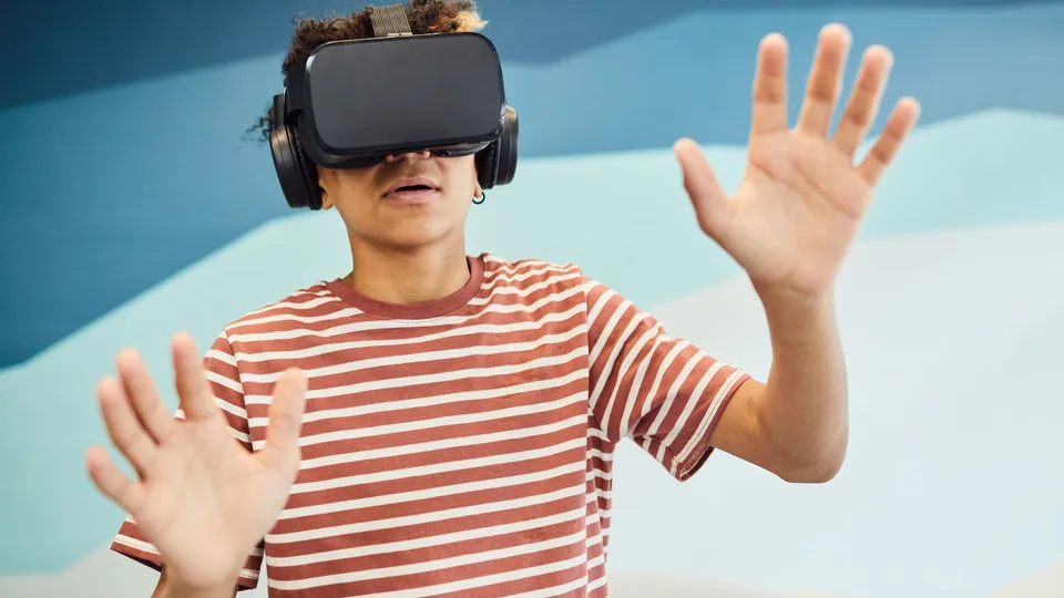 Adolescente com óculos de realidade virtual e as mãos no ar