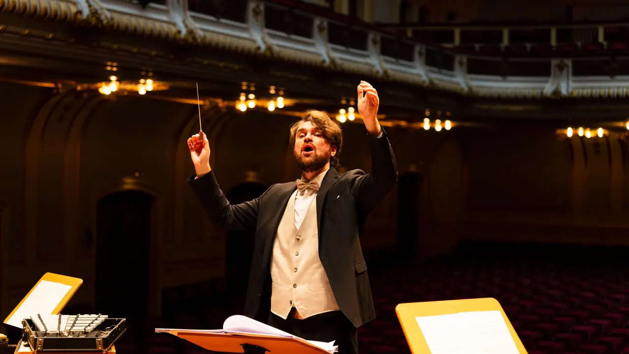 Maestro rege uma orquestra numa sala de concerto