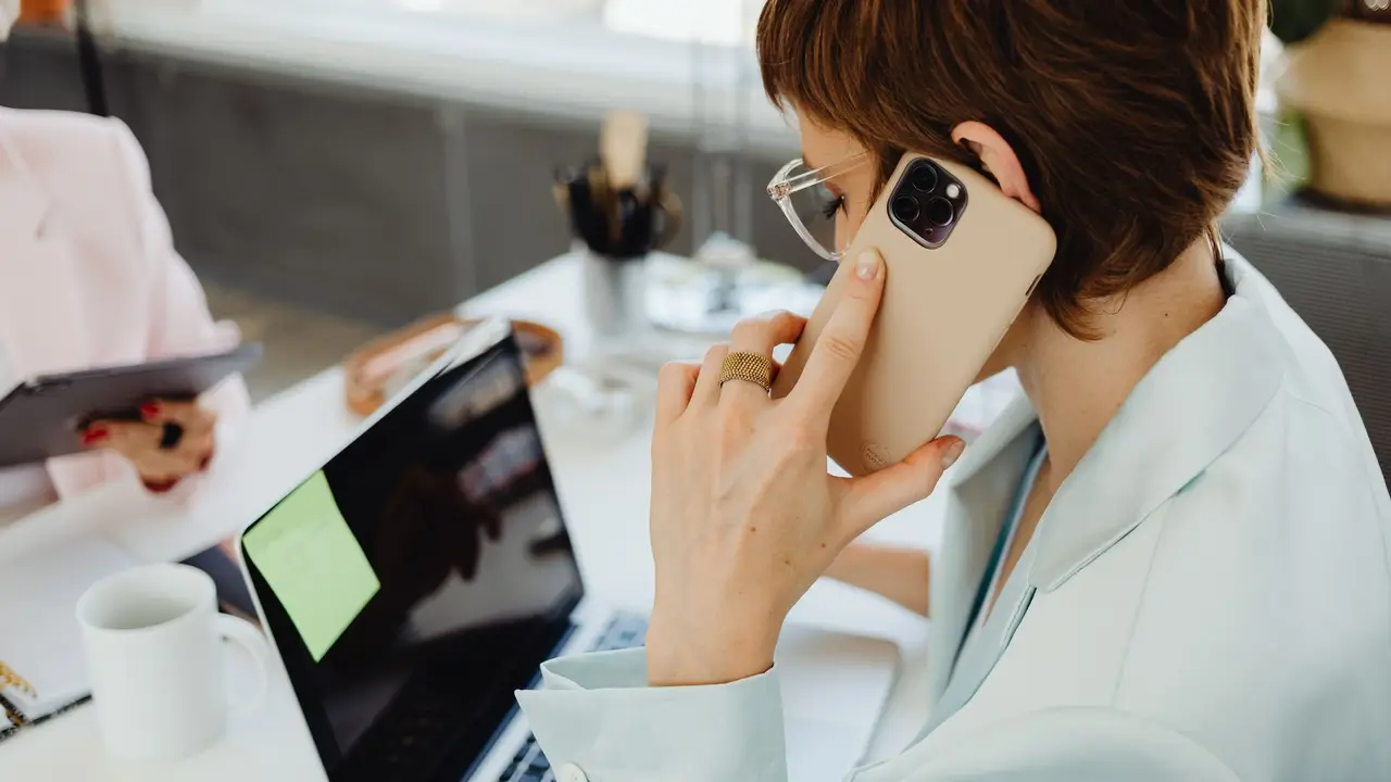 Executiva atende o telefone e trabalha no notebook ao mesmo tempo