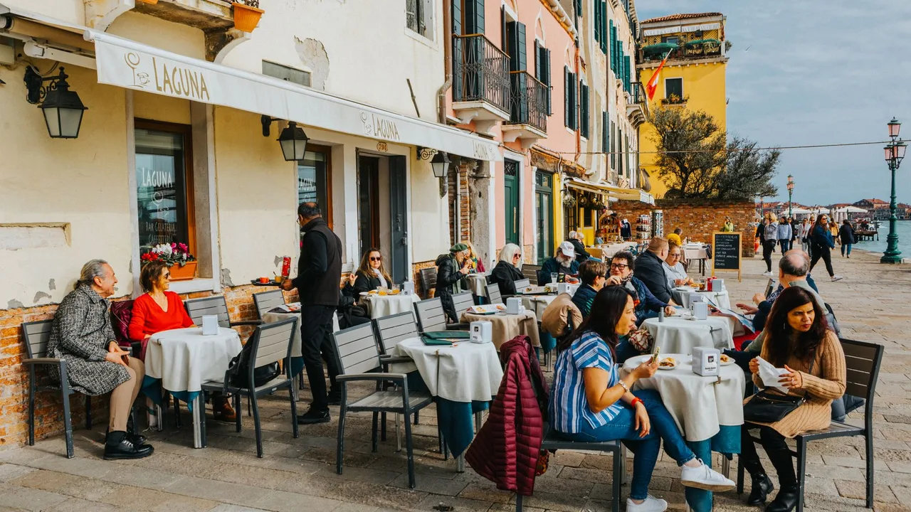 Turistas almoçando nas mesas de um restaurante na calçada